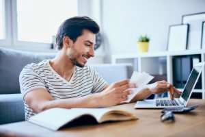 man working on taxes at desk with computer and calculator